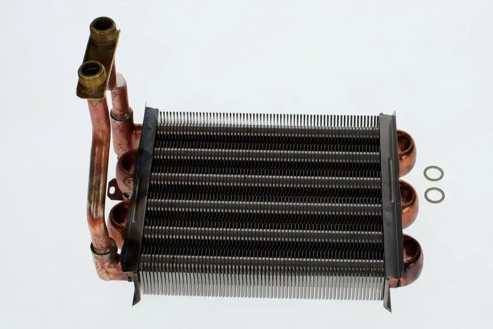 Bosch Wärmeübertrager mit Kupferrohren und einem Lamellenwärmetauscher. Zwei Dichtungsringe neben dem Gerät sind sichtbar.